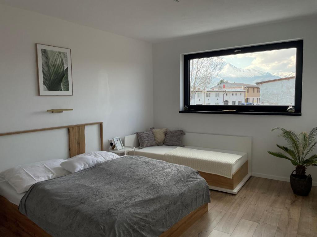 ein Schlafzimmer mit einem Bett, einem Sofa und einem Fenster in der Unterkunft Apartmány 400 in Veľká Lomnica