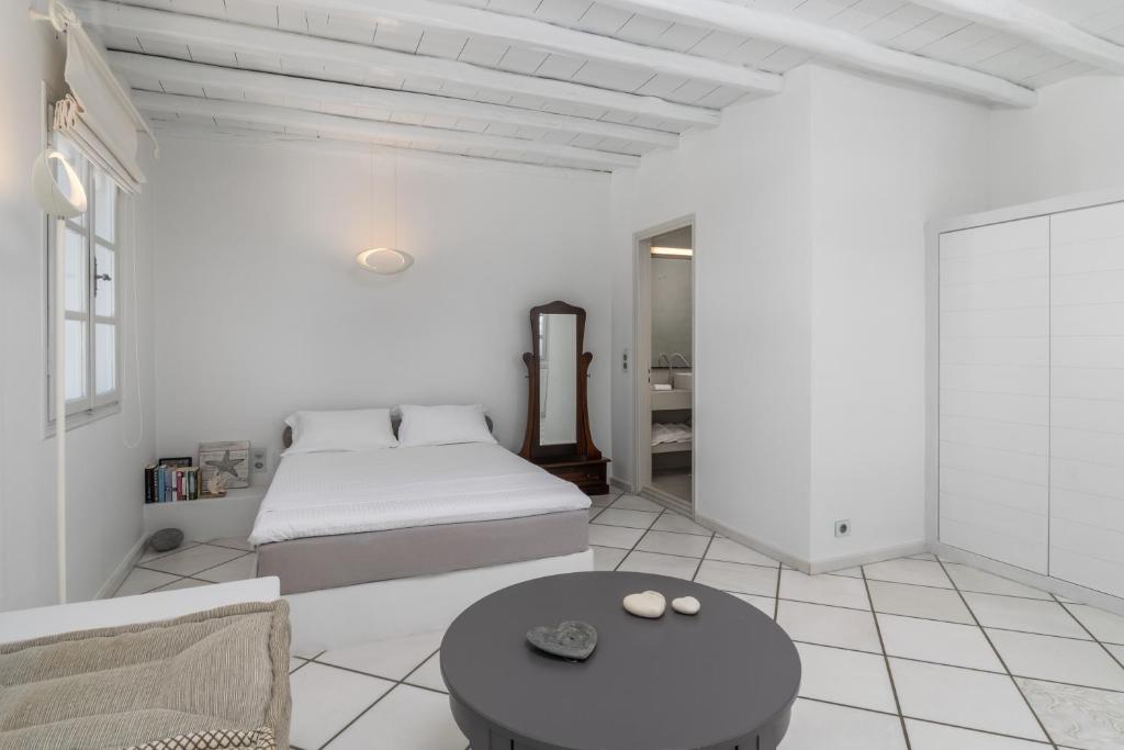 a white bedroom with a bed and a table at Archondoula Studios in Plaka Milou