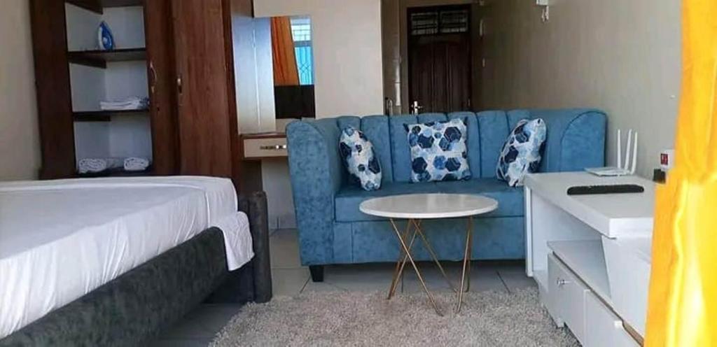 1 dormitorio con sofá azul y mesa en Well lit and loaded studio bnb en Kikuyu