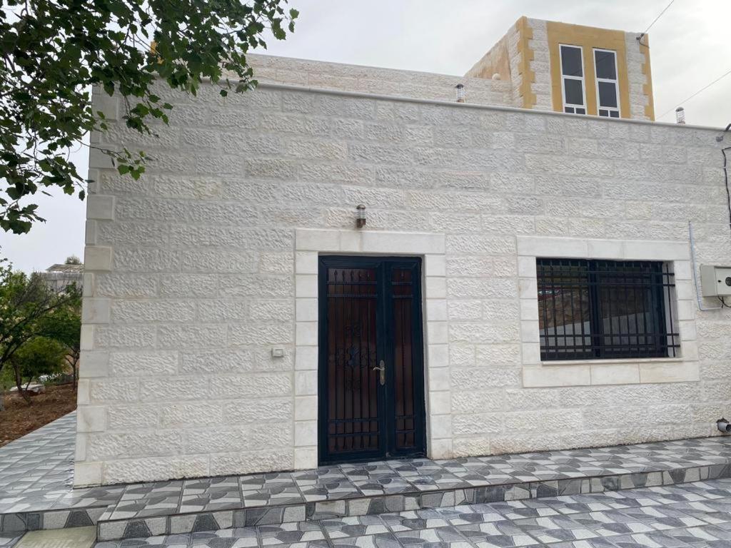 a white brick building with a black door at Moon Apartments in Jerash