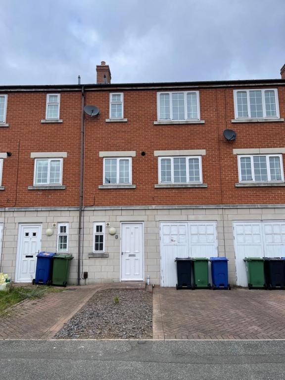 um edifício de tijolos com quatro portas de garagem brancas em Spacious 8 bed house in central Grimsby em Grimsby