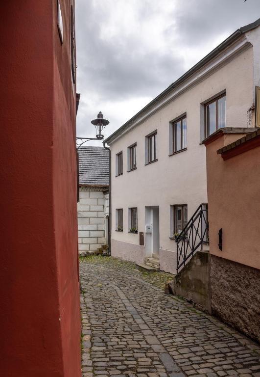 an alley with two white buildings and a stone street at Apartmány U Pavla in Český Krumlov