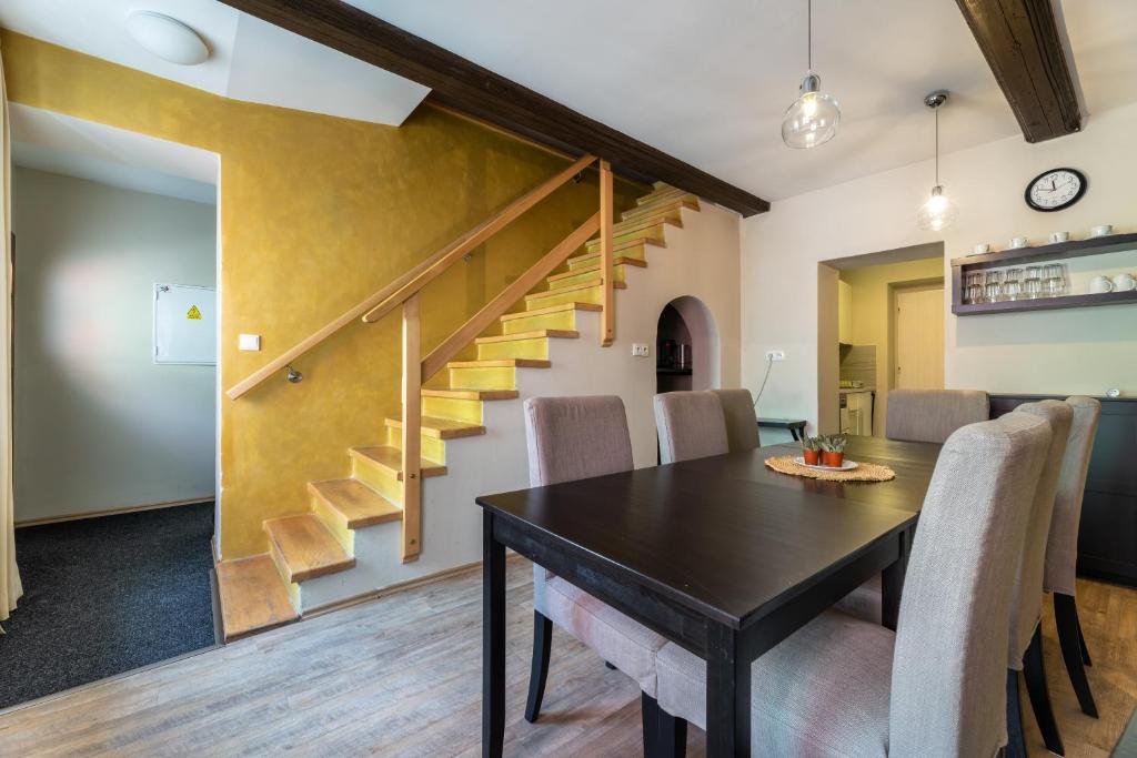 a dining room with a table and chairs and a staircase at Apartmány U Pavla in Český Krumlov