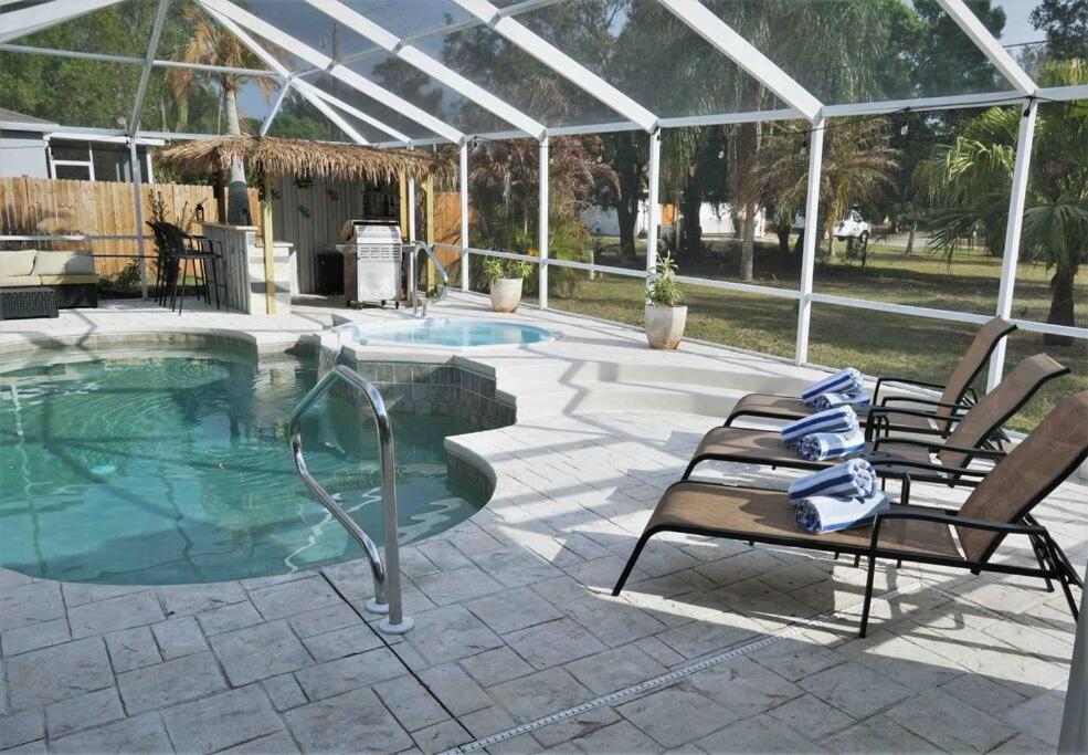 a swimming pool with two chairs and a patioitures at Peachland getaway with heated pool and tiki bar in Port Charlotte