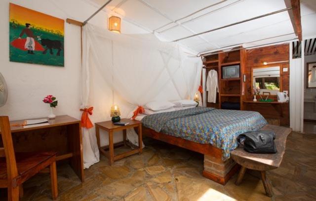 um quarto com uma cama e uma secretária num quarto em Outpost Lodge em Arusha