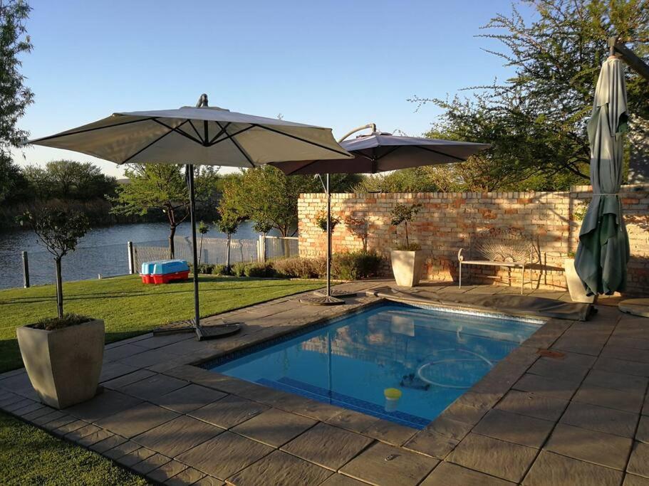 a swimming pool with two umbrellas and a swimming pool at Dam'n Devine in Parys