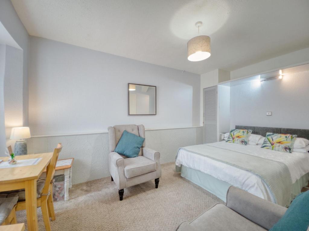 een slaapkamer met een bed, een stoel en een bureau bij Apartment 8 - Large Studio Sea Front-Ground floor -Free Parking in Paignton