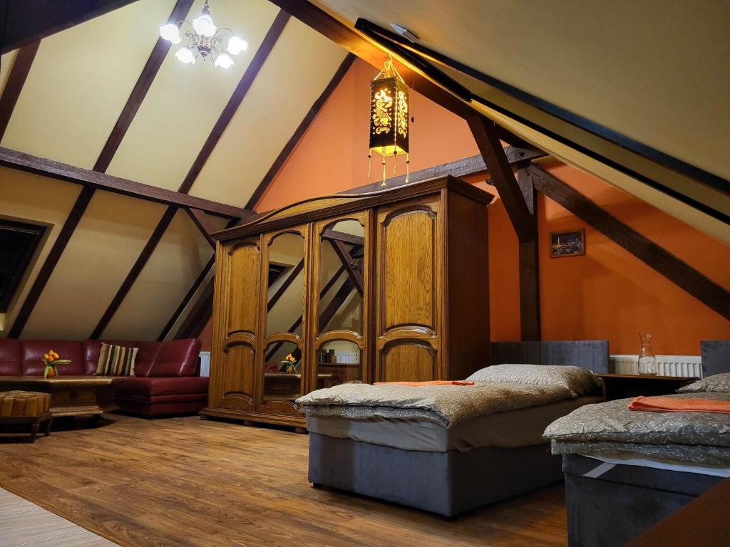 um quarto no sótão com 2 camas e um sofá em Pokoje pracownicze Witkowska em Gniezno
