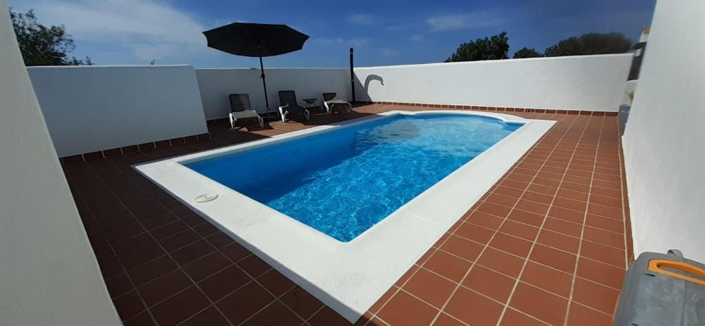 a swimming pool on a house with an umbrella at Villa Elisa in Villaverde
