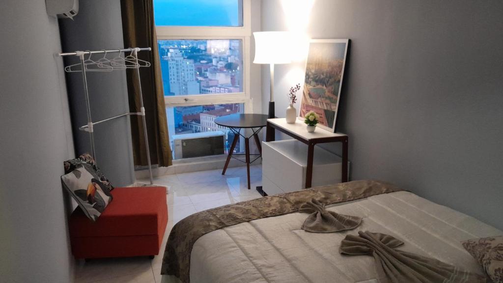 a bedroom with a bed and a table and a window at Loft 37 Centro histórico in Sao Paulo