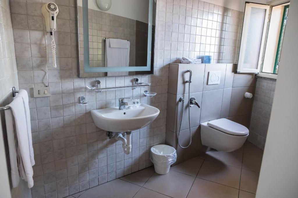 a bathroom with a sink and a toilet and a mirror at Hotel Villino Gallodoro in Taormina