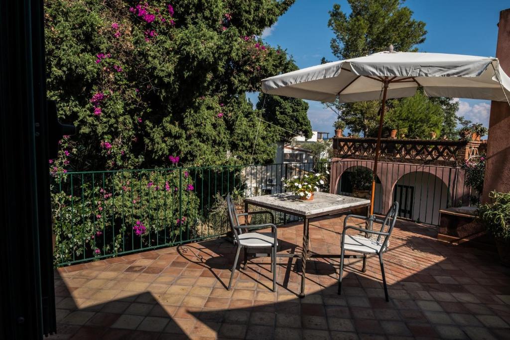 a table and chairs with an umbrella on a patio at Hotel Villino Gallodoro in Taormina