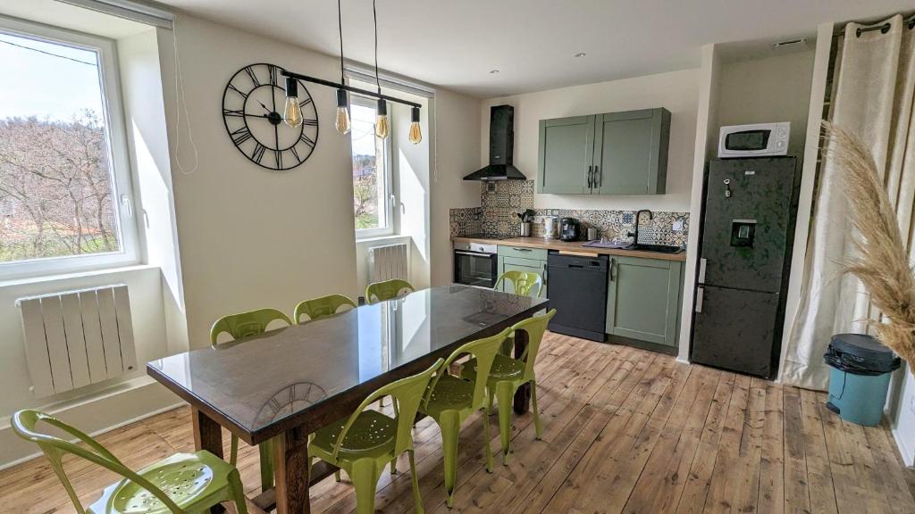 eine Küche mit einem Tisch und grünen Stühlen im Zimmer in der Unterkunft Le Puy de Côme in Saint-Diéry