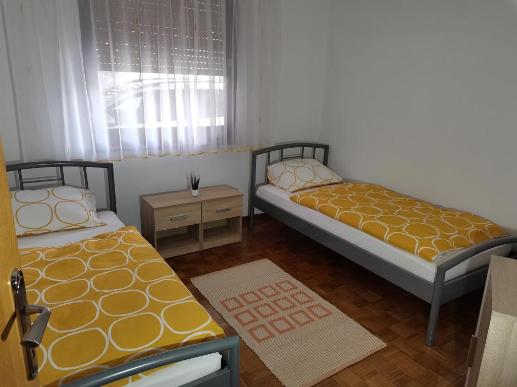 a bedroom with two beds and a table and a window at Apartma David in Most na Soči