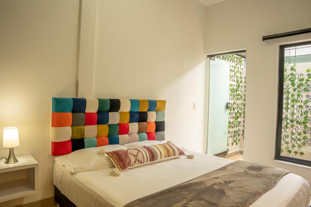Schlafzimmer mit einem Bett mit einem farbenfrohen Kopfteil in der Unterkunft FLAWLESS LODGE EN IMBANACO, Cali-Colombia in Cali