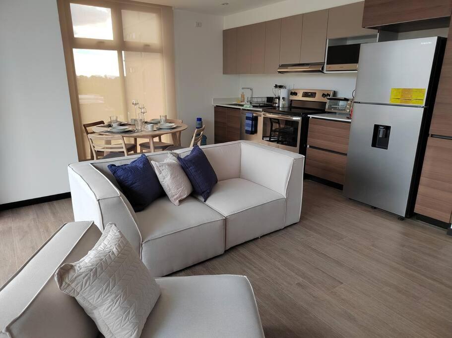 a living room with a white couch and a kitchen at Hermoso apartamento nuevo en zona 10! in Guatemala