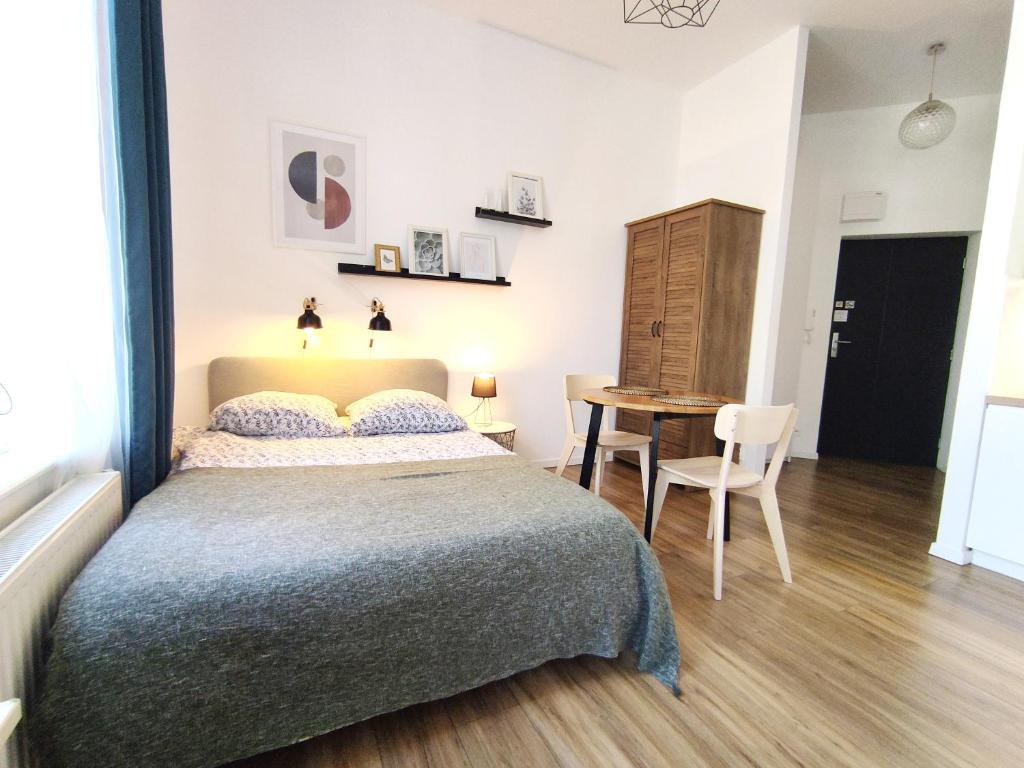 - une chambre avec un lit et une table avec une chaise dans l'établissement Apartament "Stay with Us", à Toruń