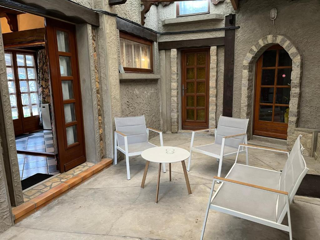 a patio with white chairs and a table and doors at Le gîte du Brouage in Chauny