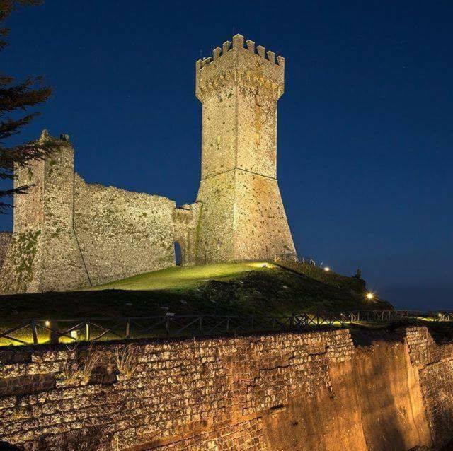una torre del castello in cima a un muro di notte di Casetta di Ghino a Radicofani