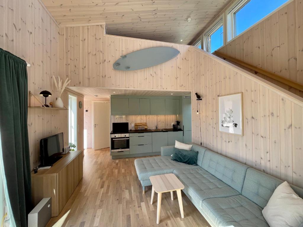sala de estar con sofá azul y TV en Fresh hytte ved Borestranden med to soverom og hems, en Klepp