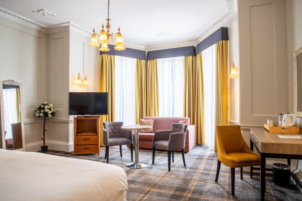 um quarto de hotel com uma cama, uma mesa e cadeiras em Arnos Manor Hotel em Bristol