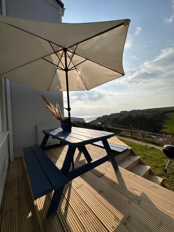 - une table de pique-nique avec un parasol sur une terrasse dans l'établissement Sea View Nook, à Porthtowan