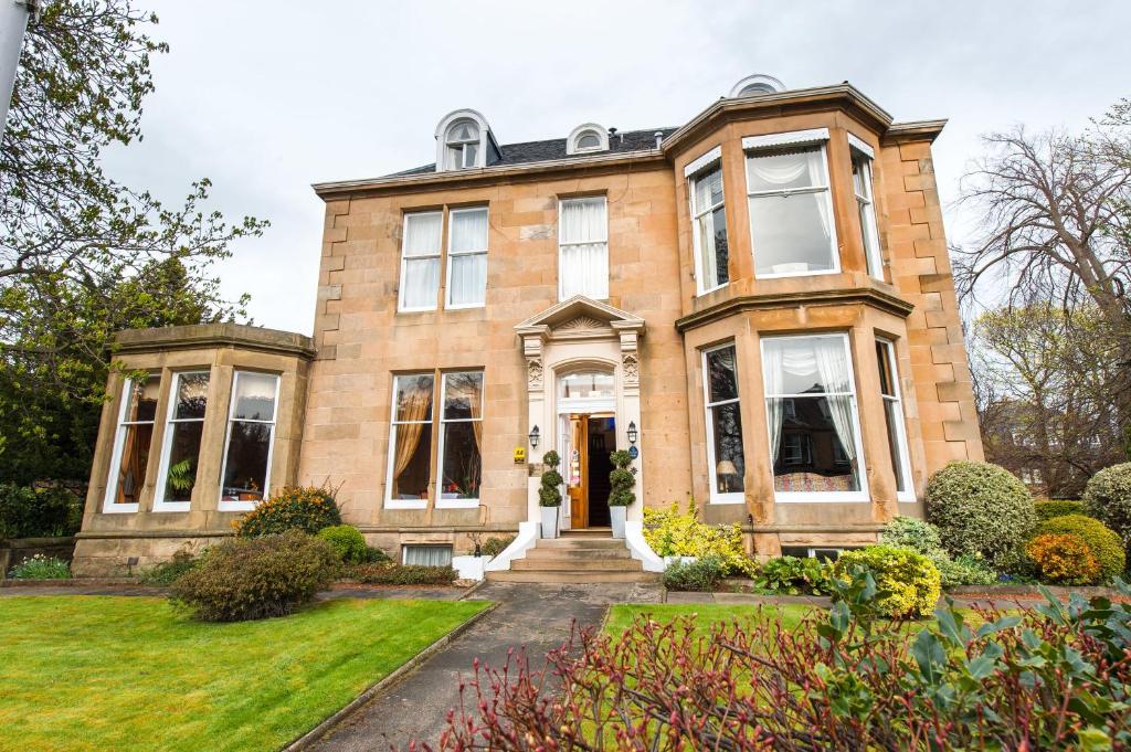 uma grande casa de tijolos com um quintal da frente em Kildonan Lodge Hotel em Edimburgo