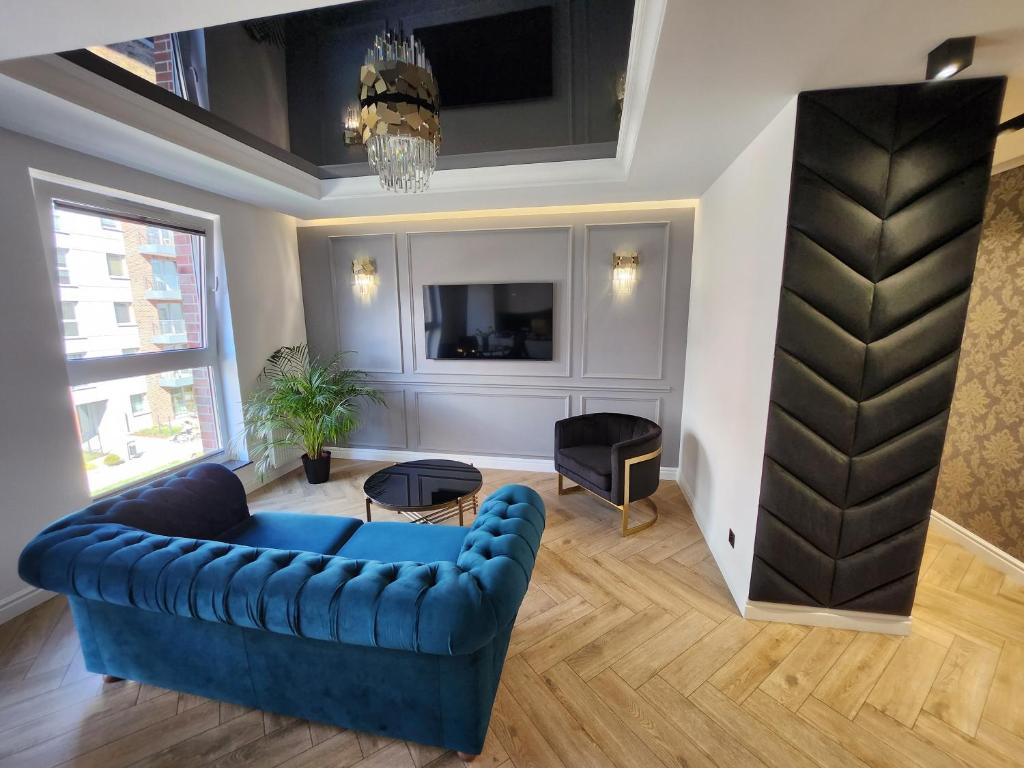 uma sala de estar com um sofá azul e uma televisão em Marina Apartments em Gdansk