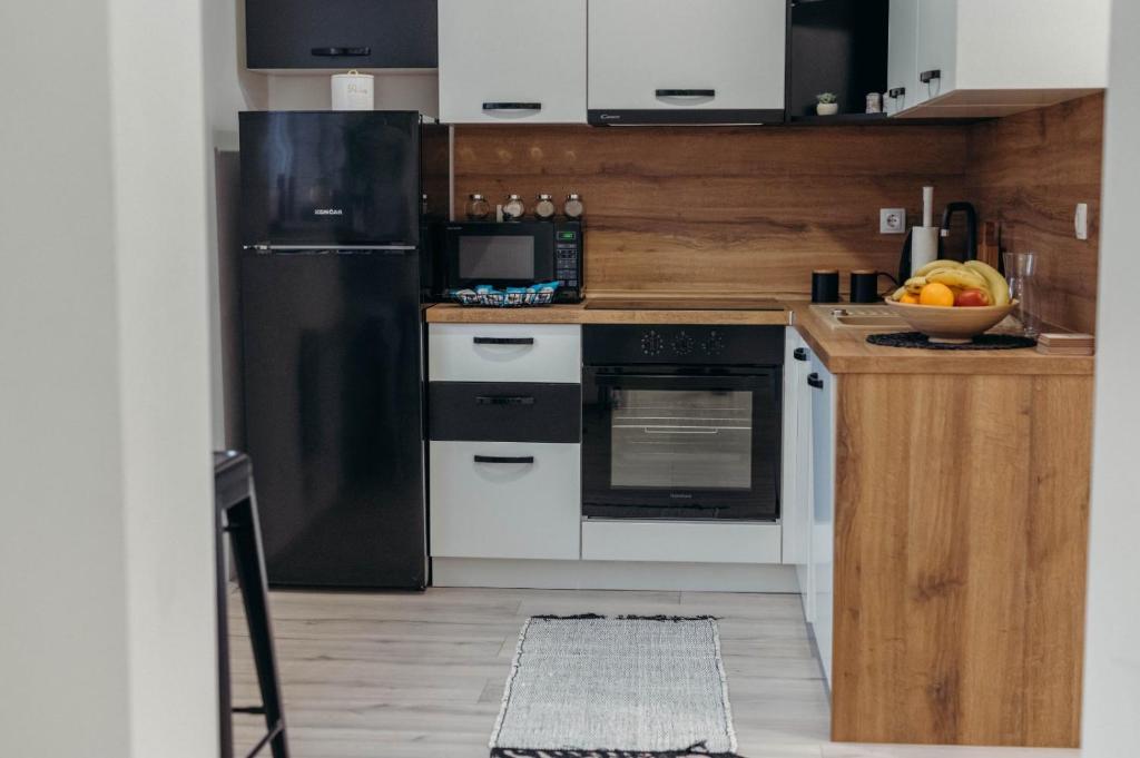 a kitchen with a black refrigerator and white cabinets at HOLY in Ðakovo