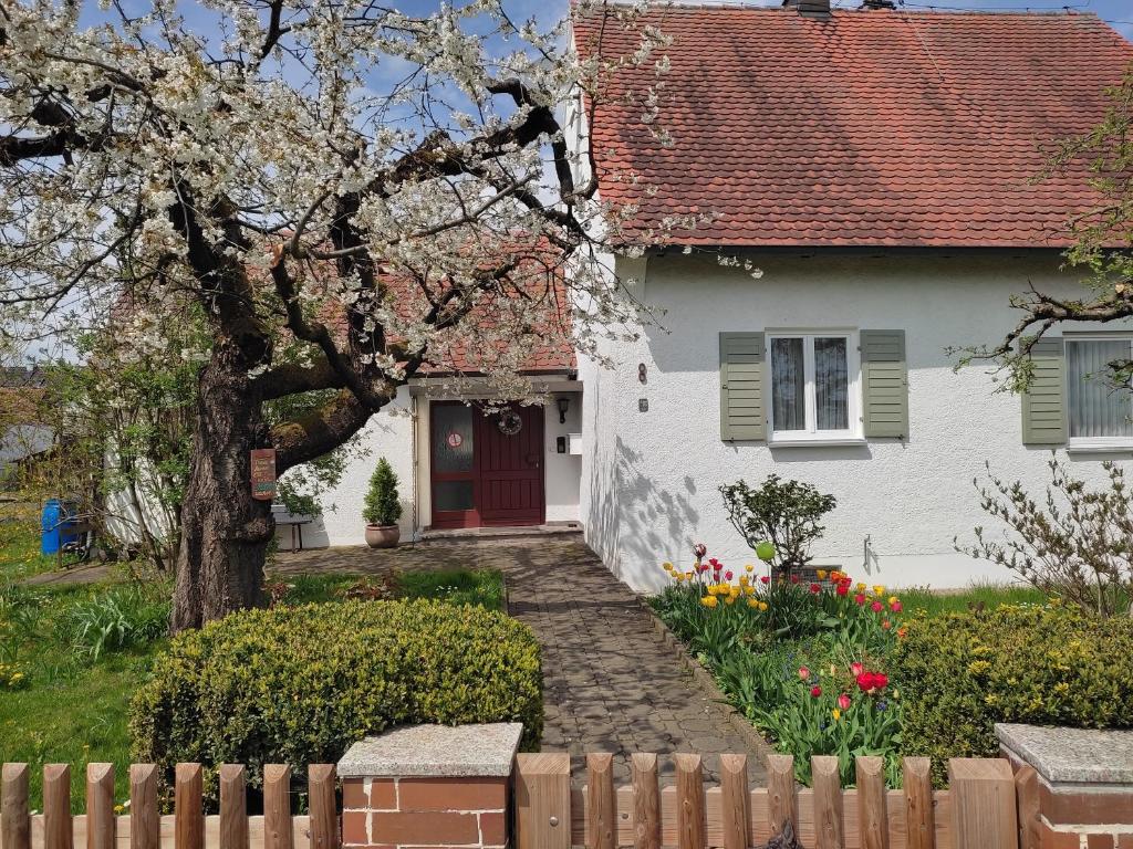 une maison blanche avec une porte rouge et une clôture dans l'établissement Oma‘s Häuschen, à Schwenningen