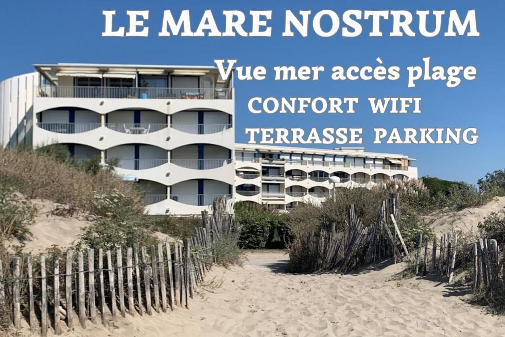 een gebouw aan het strand naast een zandstrand bij New MARE NOSTRUM-Vue Mer-Wifi-Accès Plage-Parking-TOP PROS SERVICESConciergerie La Grande Motte in La Grande-Motte