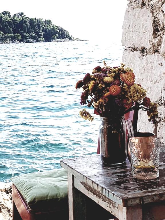 um vaso de flores sobre uma mesa ao lado da água em Apartments Maxim em Tivat