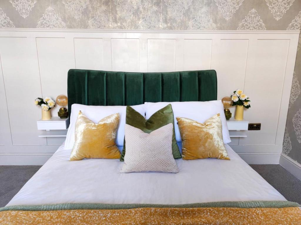 a bed with four pillows and a green headboard at Merchant House in Bootle