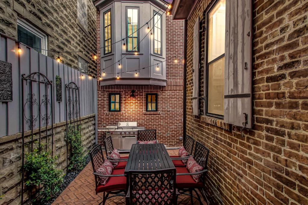 a patio with a table and chairs and a balcony at The Lyons House - Luxe Historical Home - Parking Included in Savannah