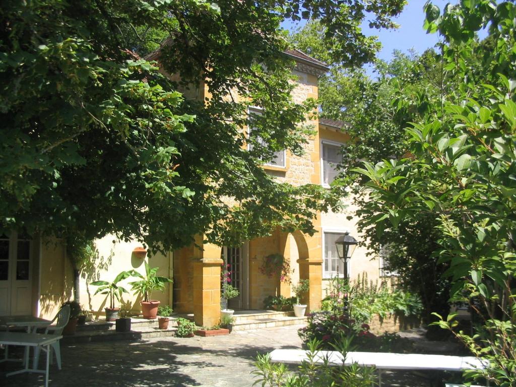 a yellow house with trees and a patio at Le Petit Chaperon Rouge in Coux-et-Bigaroque