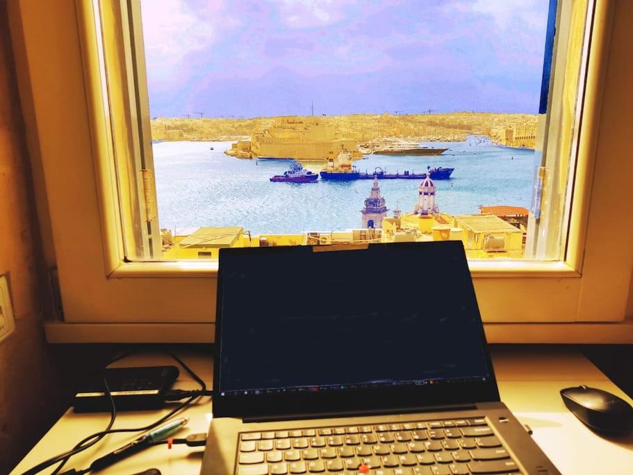 een laptop op een bureau voor een raam bij Cove 532 by Savynomad Harbour Residences wow View in Valletta