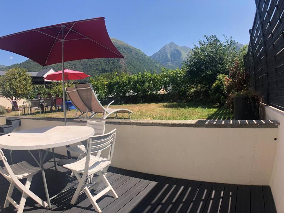 einen Tisch und Stühle mit Sonnenschirm auf dem Balkon in der Unterkunft Maisonnette avec terrasse, jardin et poêle à bois in Pierrefitte-Nestalas