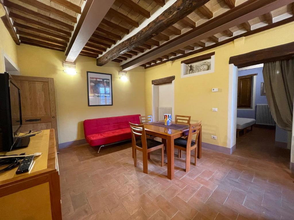 sala de estar con mesa y sofá rojo en Valdorcia, en San Quirico dʼOrcia