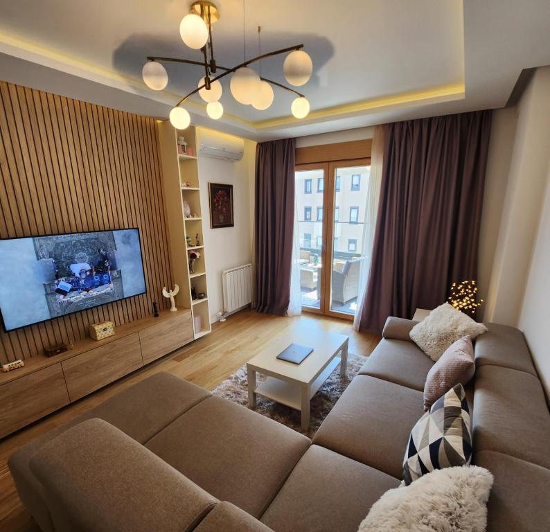 een woonkamer met een bank en een tv bij APARTMAN FLORENCE in Mirijevo