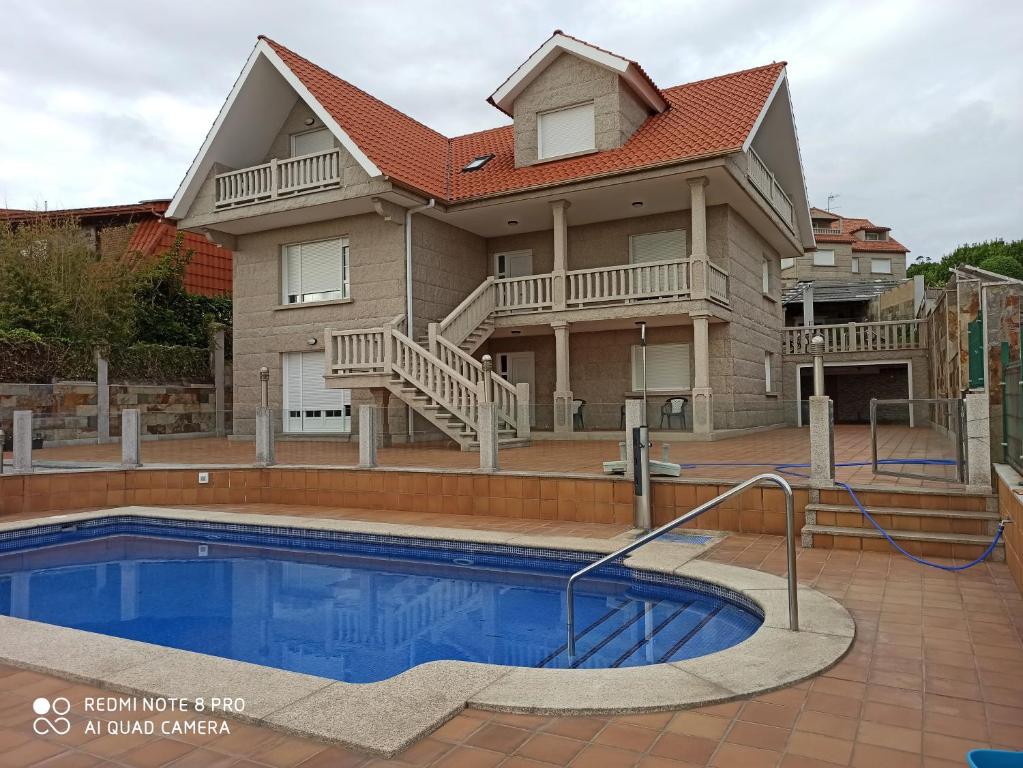 dom z basenem przed nim w obiekcie Duplex en Sanxenxo con piscina y vistas al mar w mieście Sanxenxo