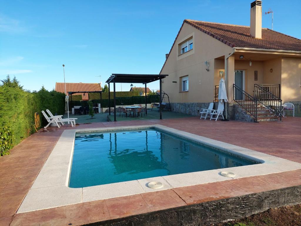 - une piscine en face d'une maison dans l'établissement Disfrutar y relajarse en el Robledal, à Zarzuela del Monte