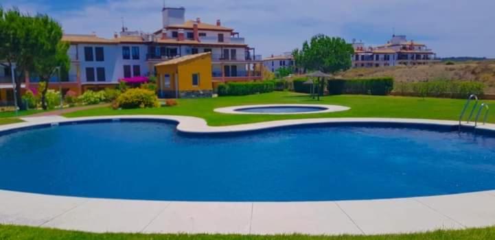 a large blue swimming pool in front of a building at APARTAMENTO MANUELA RESIDENCIAL **VISTA ESURI** in Ayamonte