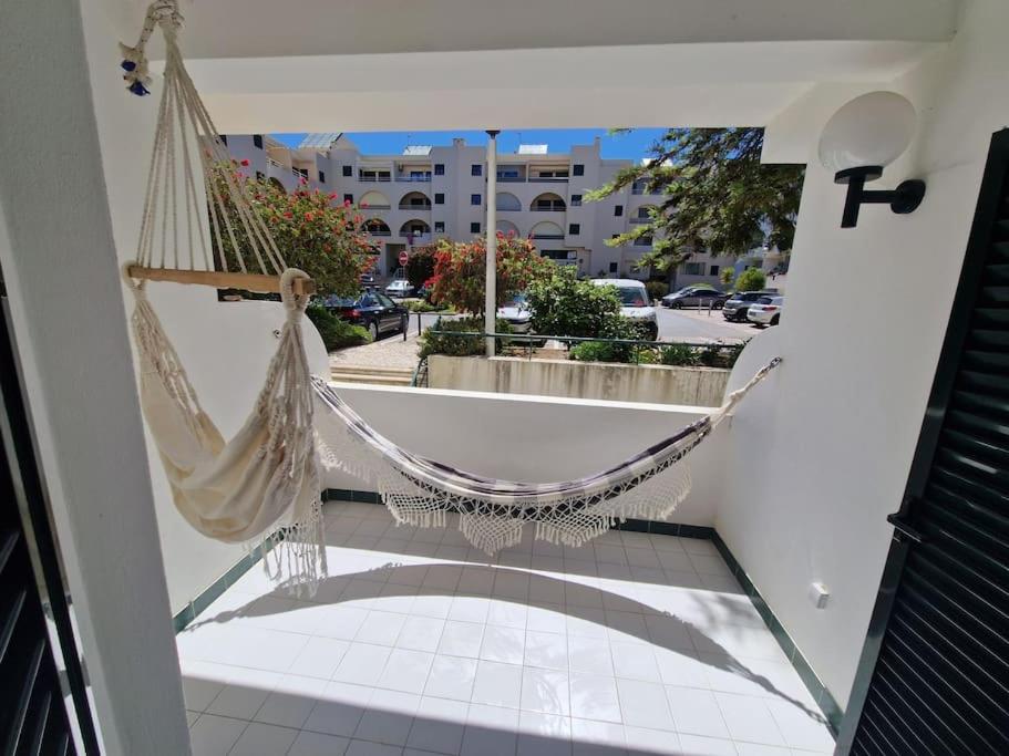 a hammock on a balcony with a view of a street at Charming Beachside Apartment- The Perfect Getaway! in Albufeira