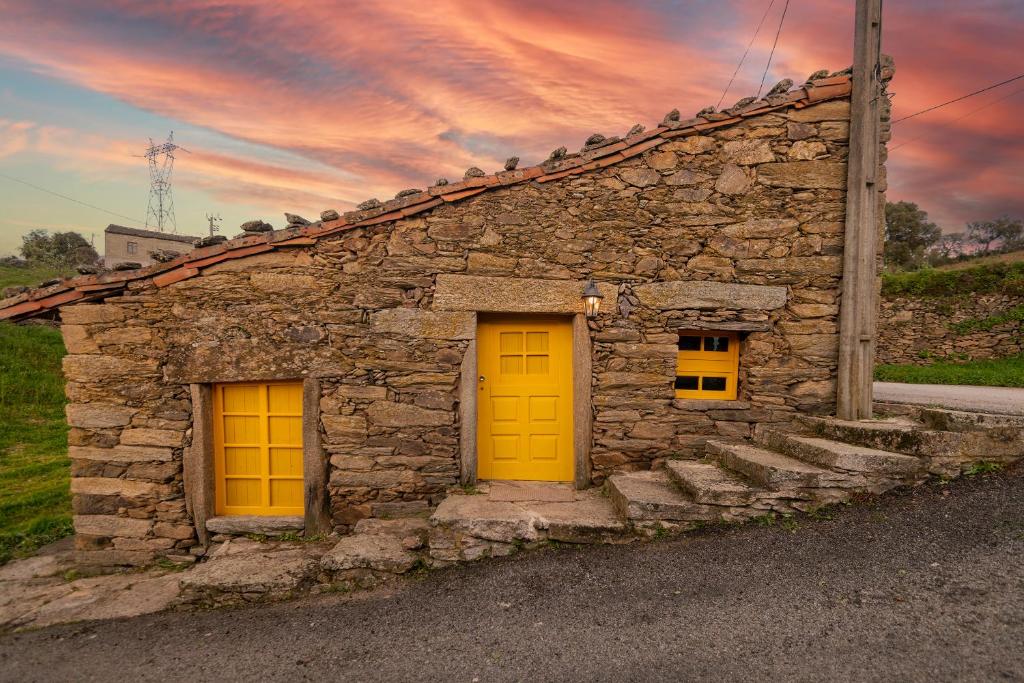 a stone building with two yellow doors and stairs at Lagos Com Sabor Guest House 