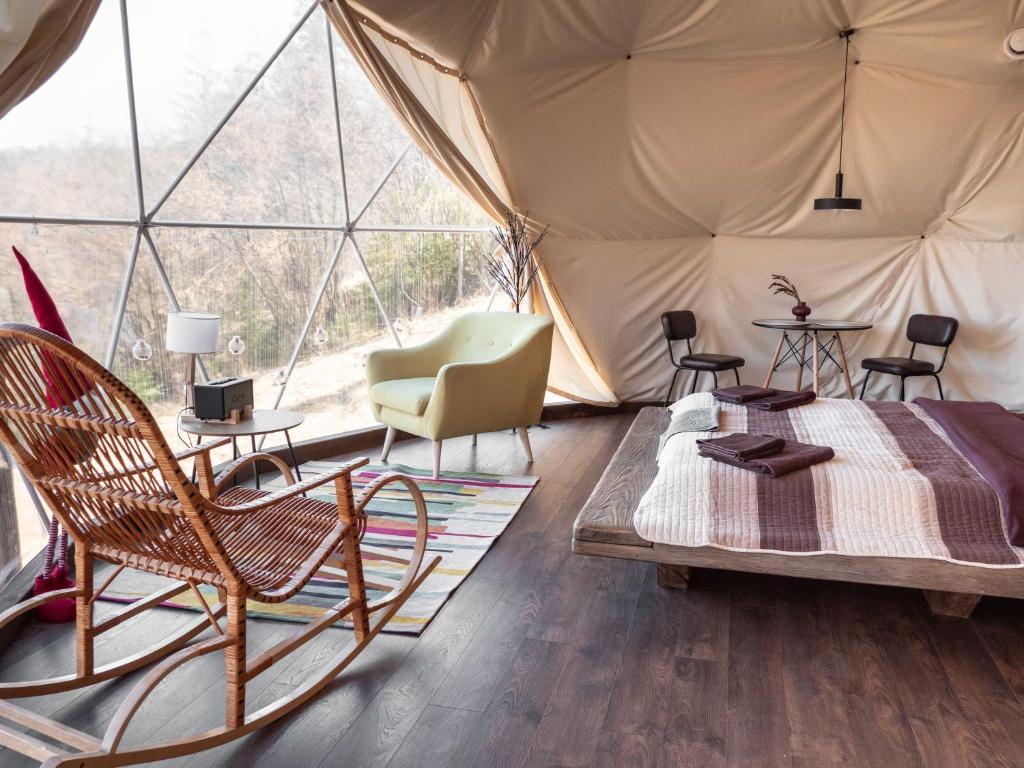 Zimmer mit einem Bett und Stühlen in einem Zelt in der Unterkunft SlavskoGlamping in Slawske