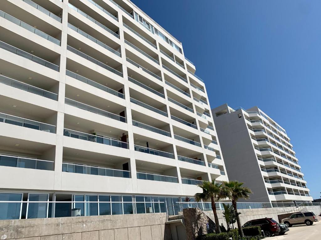 a large white building with palm trees in front of it at La Jolla Excellence, Exclusive Front Beach! in Rosarito