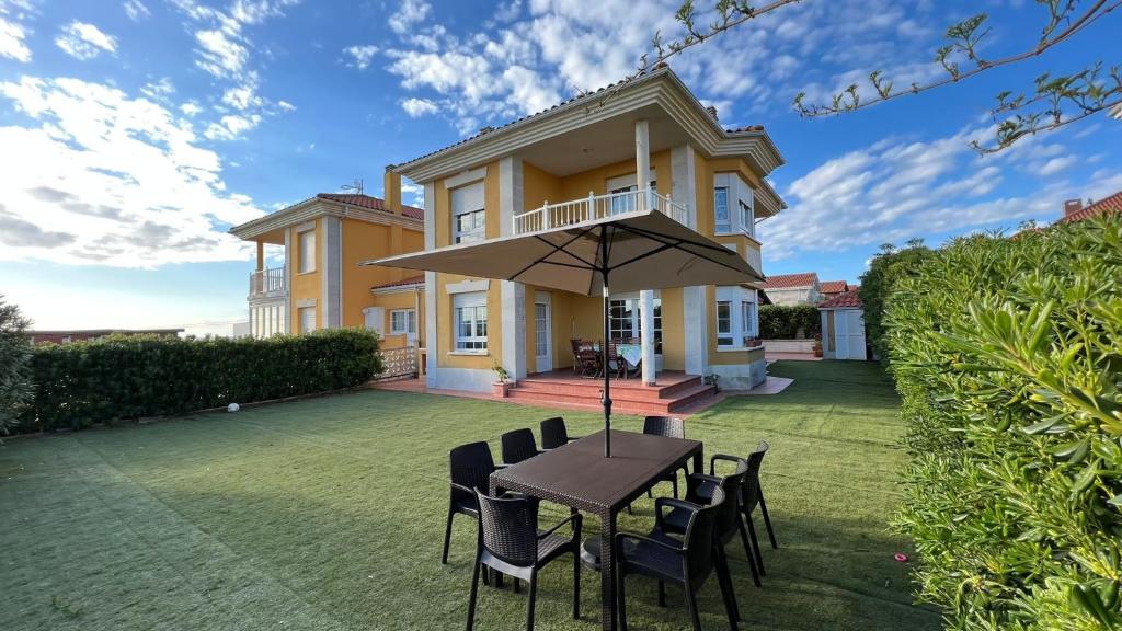 a table with chairs and an umbrella in front of a house at Villa Ojerada - 12804 in Ajo
