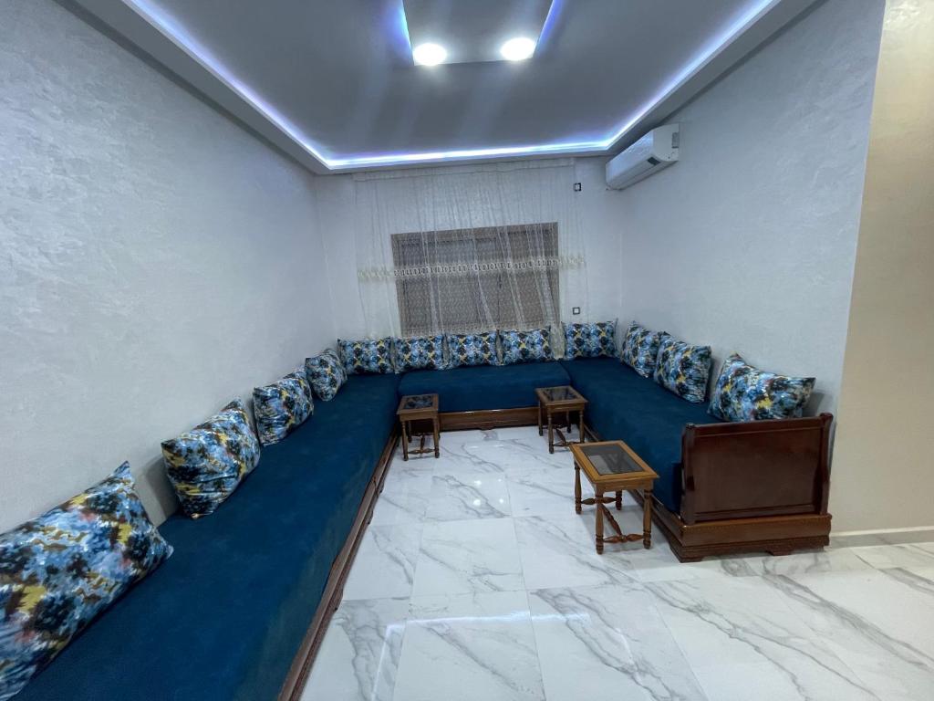 een wachtkamer met een blauwe bank en een tv bij Promotion Appartement chic et calme in Fès