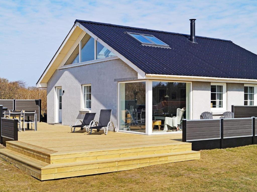 een huis met een houten terras ervoor bij Three-Bedroom Holiday home in Løkken 32 in Løkken