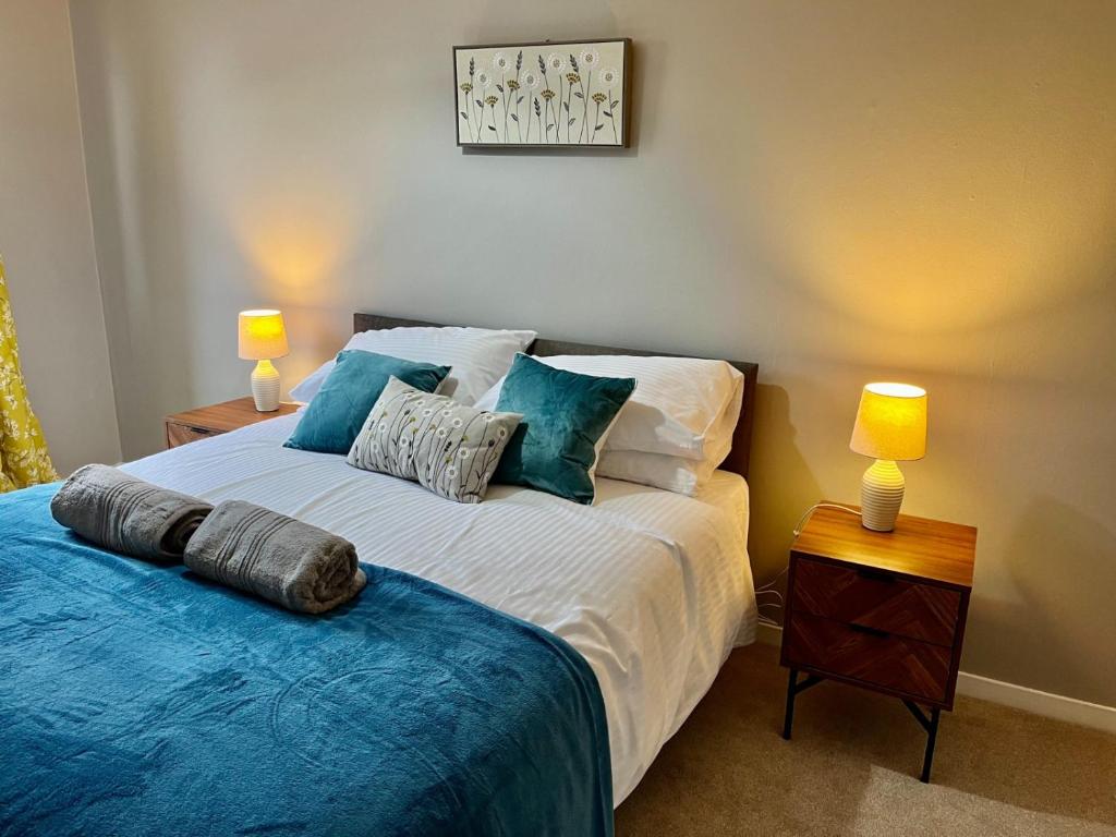 1 dormitorio con 1 cama con sábanas azules y 2 lámparas en Canada House - Sleeps 6 -3 King or 6 Single Ideal for contractors, en Warrington